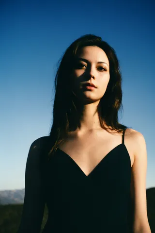 Photorealistic portrait of a woman with captivating eyes and skillful makeup, set against a clear blue sky with volumetric lighting and intricate detail.