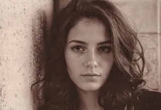 Portrait of a 26-year-old French woman with detailed eyes and natural skin, featuring hard shadows and film grain effect.