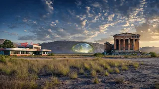 Panoramic desert landscape featuring a retro diner on the left, ancient Greek-style ruins on the right, and a glowing mysterious portal in the mountainous background under a dramatic cloudy sky.