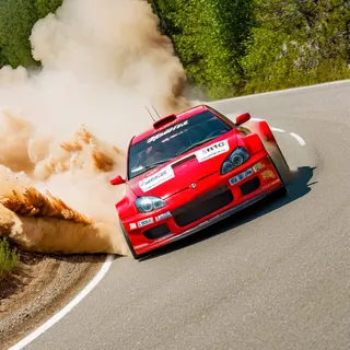 Red rally car taking a sharp turn on a paved road creating a large dust cloud, captured in a professional photoshoot with film grain style and haze effects