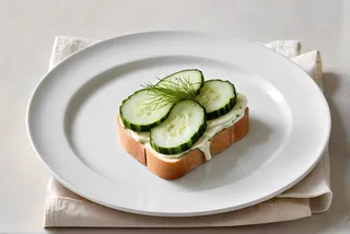 Top view of a cucumber sandwich on white bread with mayo on a white plate, minimalist clean background, fresh and elegant presentation