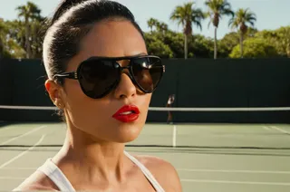 Close-up of a woman wearing luxury black sunglasses and red lipstick with sweat drop on her face, standing on a sunny tennis court with palm trees in Florida, cinematic lighting.