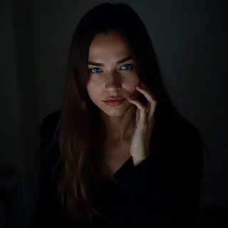 Cinematic portrait of a woman with long hair, blue eyes, and a black shirt, illuminated by dramatic high contrast lighting with film grain effect.