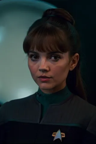 Closeup of a young woman in a teal and black DS9 Starfleet uniform, standing in a sci-fi space station with a bokeh background