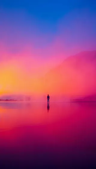 Une silhouette solitaire se reflétant sur un lac calme au coucher du soleil, entourée de teintes vibrantes de rose, orange et bleu avec une brume légère et des montagnes lointaines.