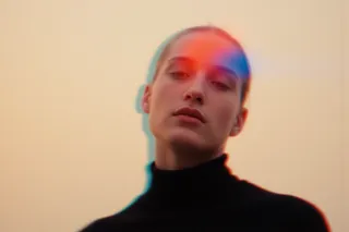 Portrait of a woman wearing a black turtleneck with soft blur and red-blue color distortion on her face