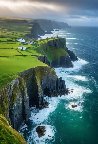 Dramatic aerial view of emerald-green cliffs along the Irish coastline plunging into the Atlantic Ocean, with morning mist, ancient castle ruins, and stone walls dividing grassy fields.