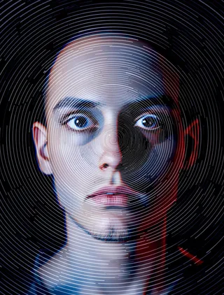 A close-up portrait of a person's face with wide, dilated pupils and unblinking eyes, overlaid by a hypnotic white spiral pattern on a black background and distorted with red and blue color offsets.