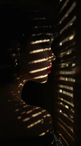 A side-profile portrait of an oriental woman with chiaroscuro lighting casting striped shadows across her face and shoulder, highlighting her red lips and silky hair.