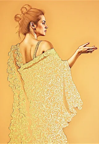 Pencil drawing portrait of a woman with a messy bun updo, wearing a long flowing sheer dress adorned with gold ornamental swirls, set against a plain beige background.