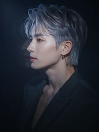 Dramatic close-up side profile of a K-pop star with silver hair, wearing a black jacket and a silver ear chain, illuminated by a focused white spotlight against a black background.